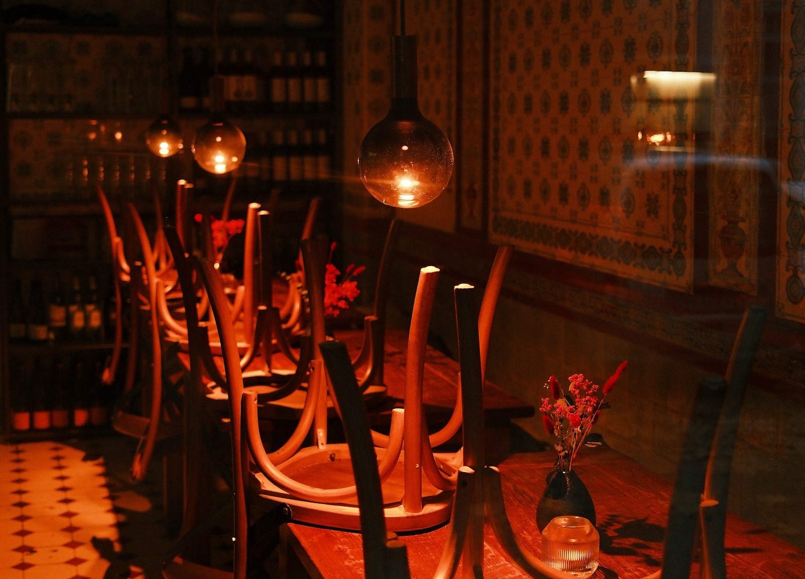 A dining room after closing, chairs upturned on the tables under warm pendant lamps